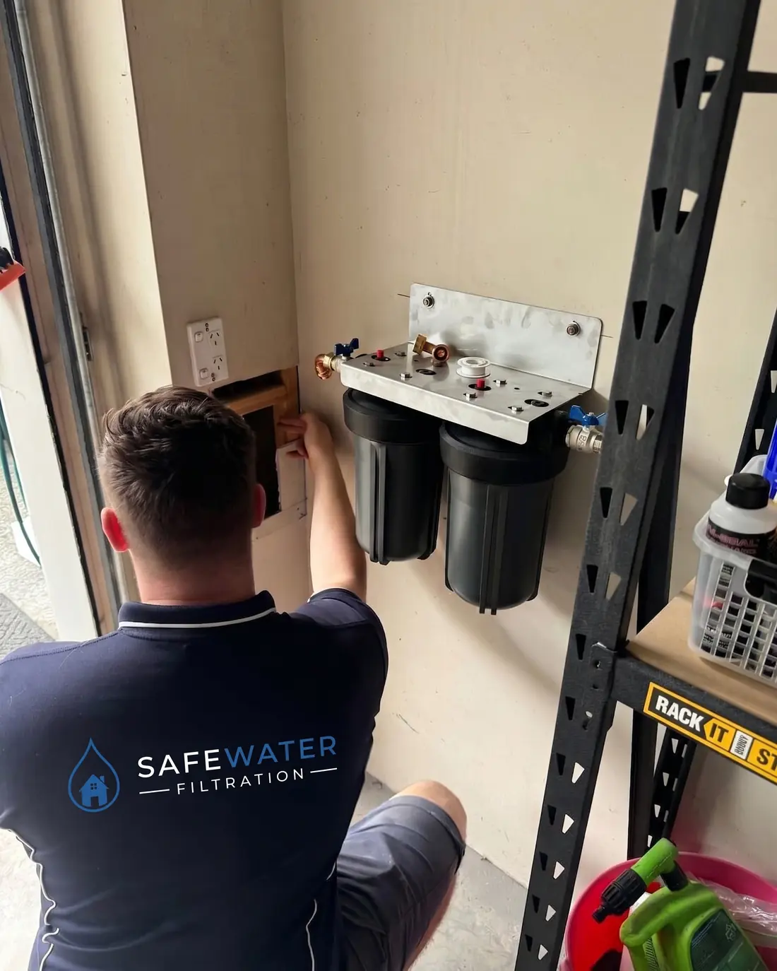 Twin whole-house filter housings mounted on a stainless steel bracket in a Sydney garage with isolation valves fitted