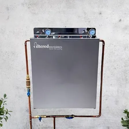 Whole house water filtration system mounted on an external wall with copper pipework and isolation valves