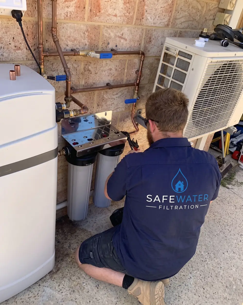 Water Filtration Sydney plumber installing a twin whole-house filtration system beside a Sydney home